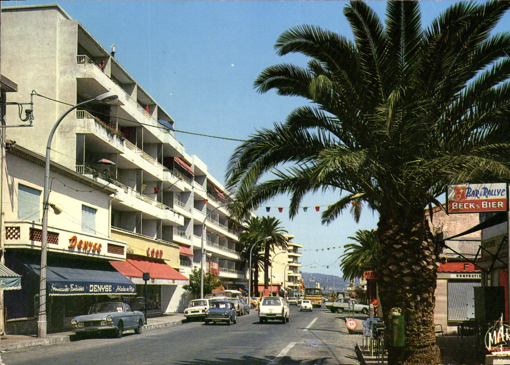 Cavalair-sur-Mer — Rue principale avec palmiers et commerce — Les Éditions 4MÃ¨T, n°8236