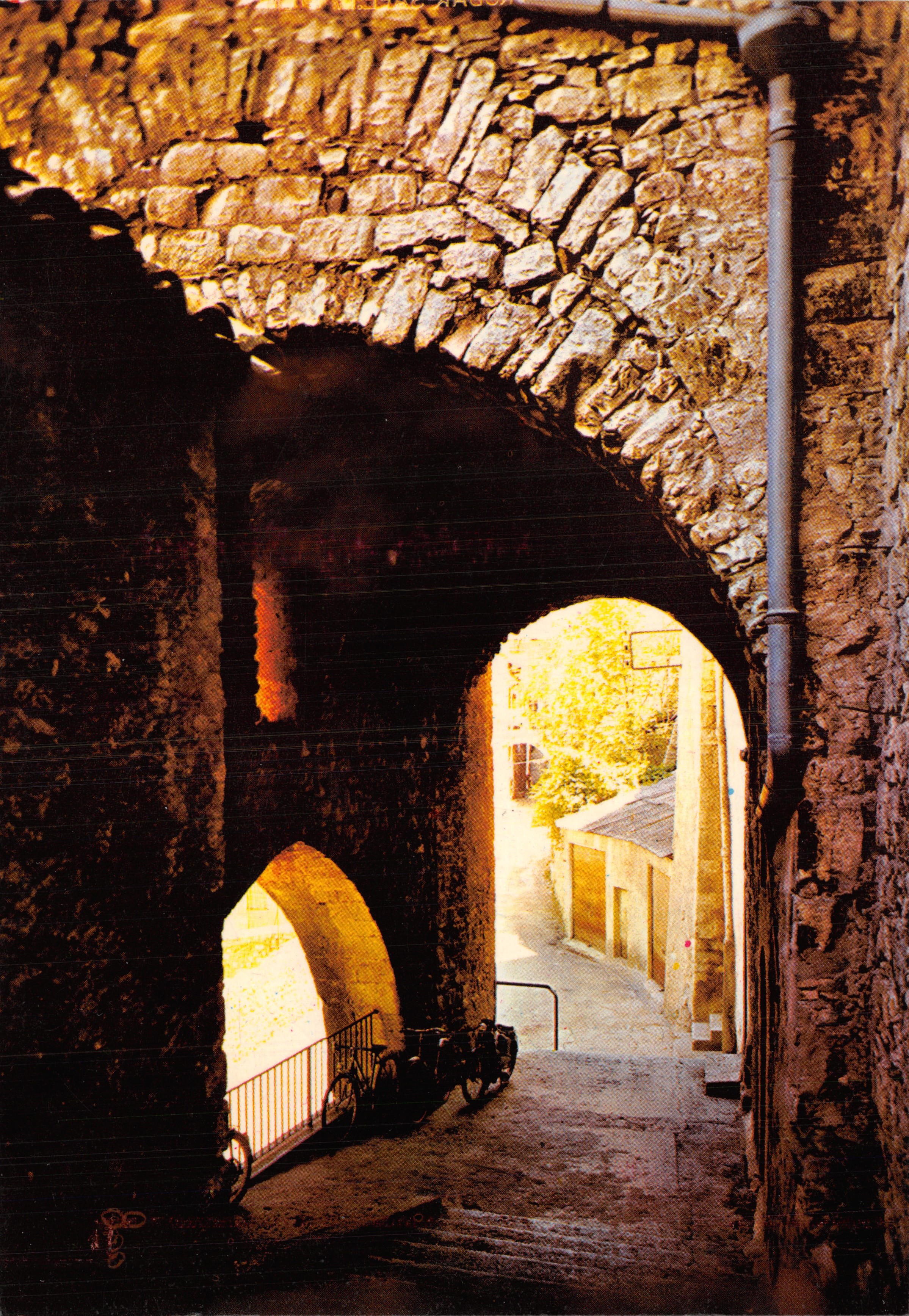 Sisteron (B.A.) — View of an old stone porch on a sloping street — Les Editions « MAR »
