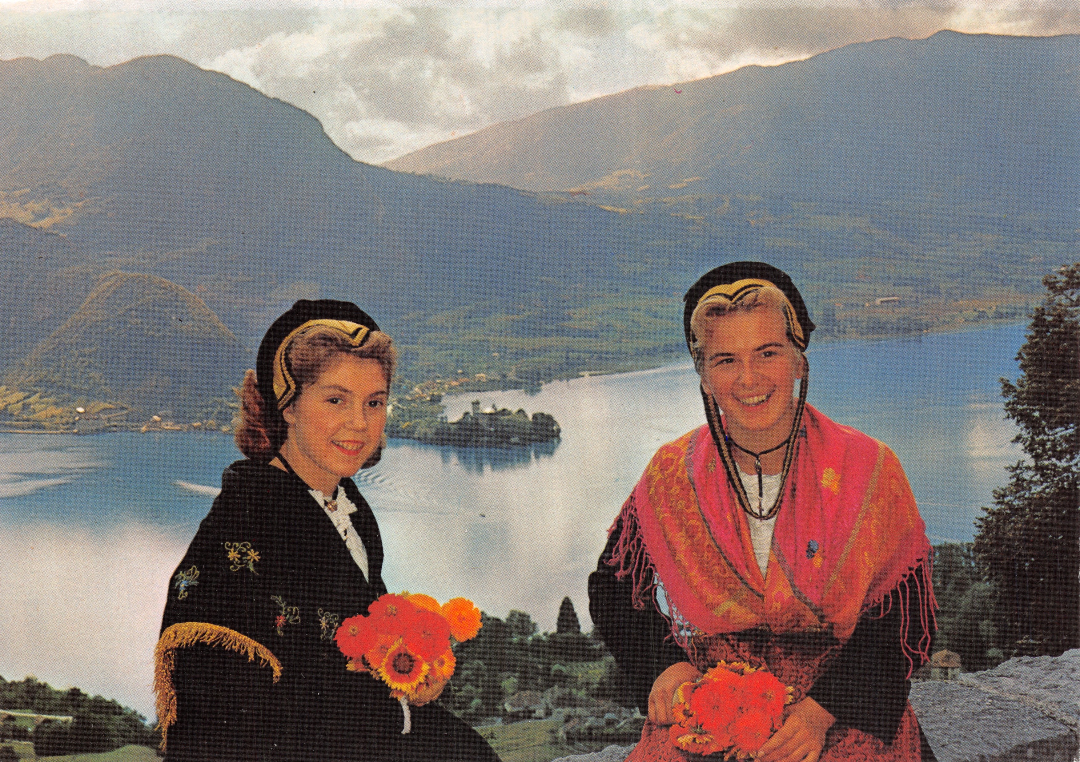 Two young women in traditional attire — lake and mountains in the background — Edition Les Photographies de G. Rossat-Mignod