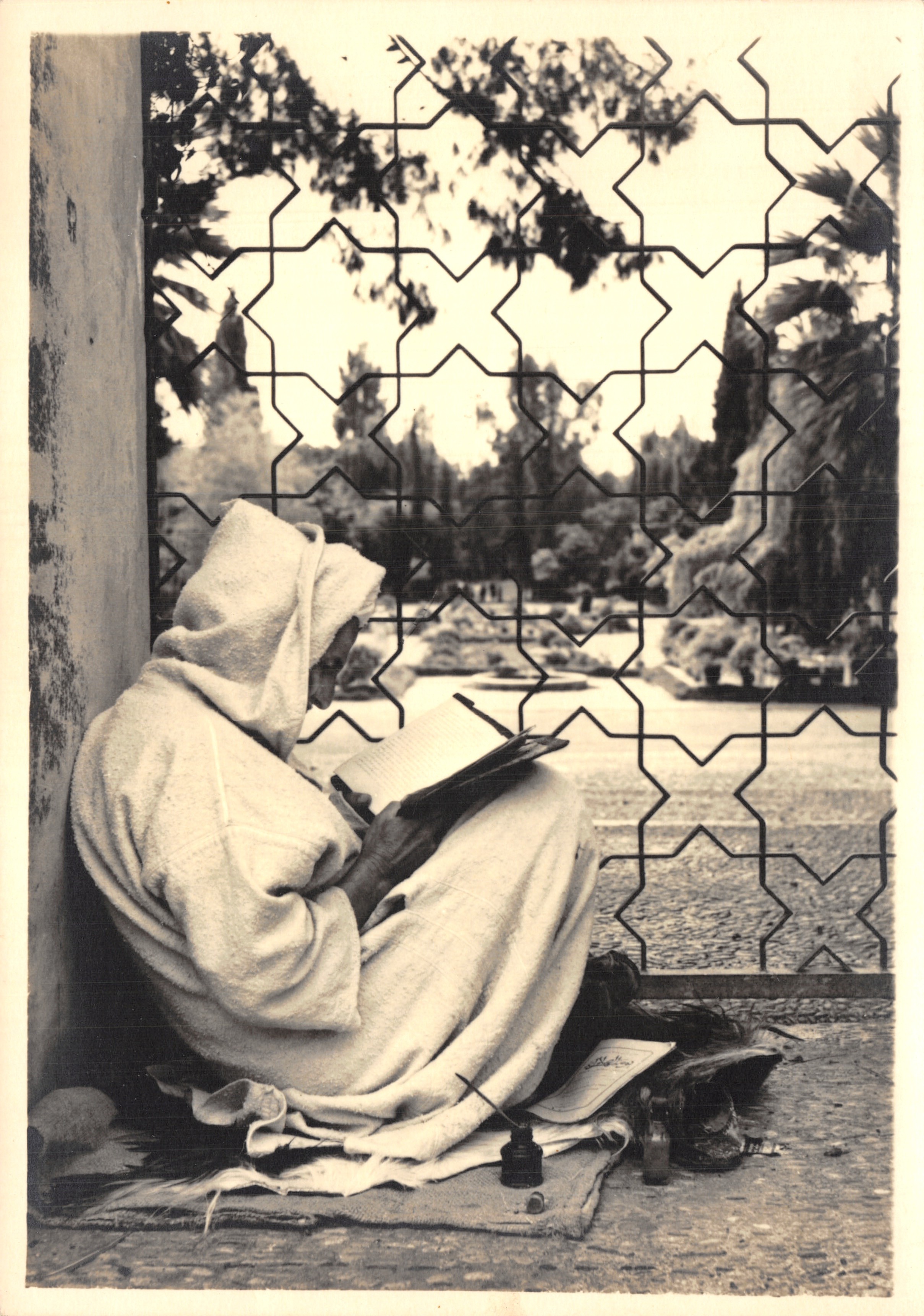 Man in djellaba die leest — tuinscene achter geometrische hekken — Photos Éditions Art-Maroc, Rabat, n°1/125