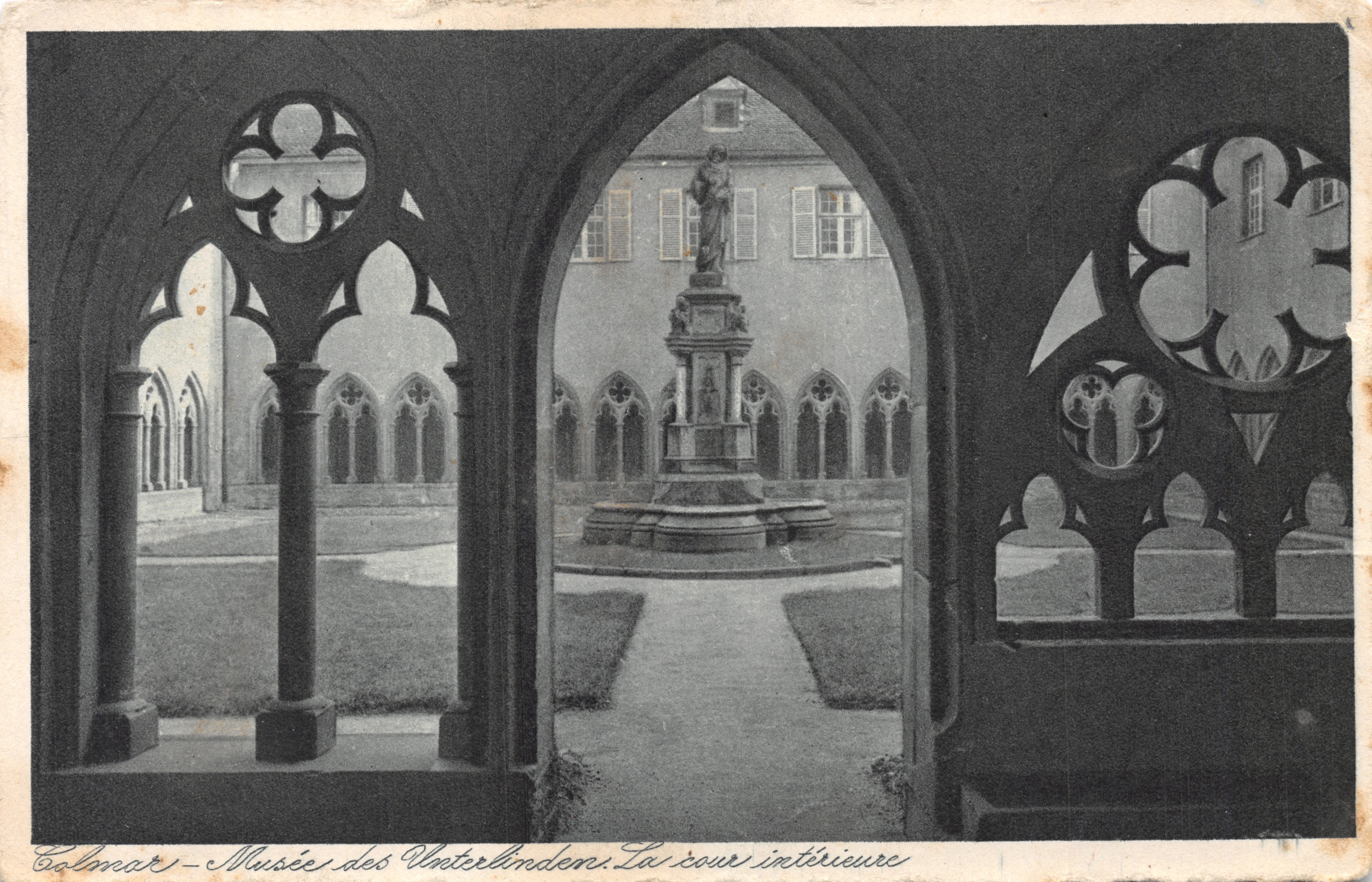 Colmar - Museos Unterlinden. La plaza interior — vista encuadrada por arcadas góticas adornadas con vidrieras de rosas