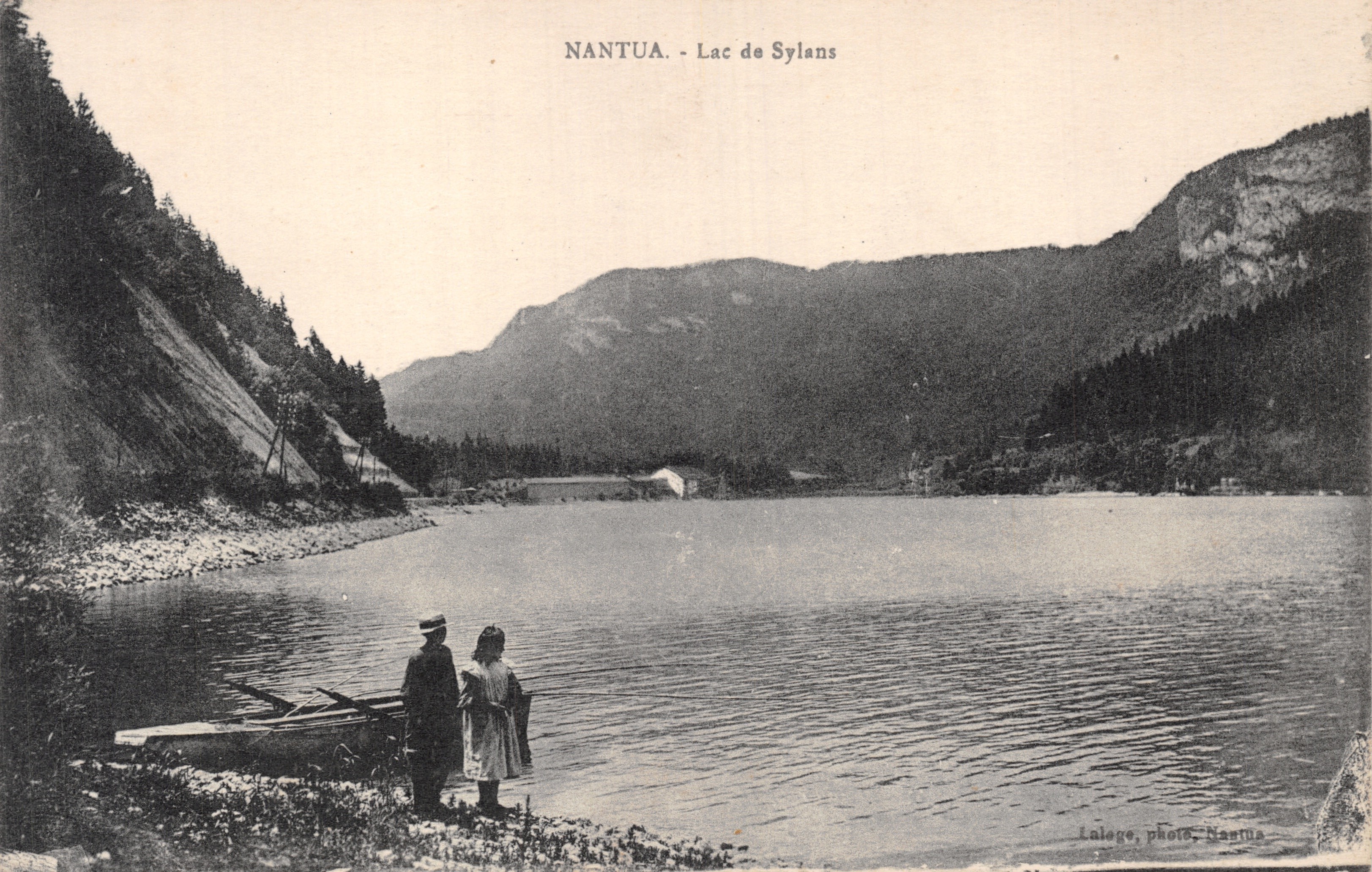 Nantua - Lago di Sylans — vista del lago circondato da montagne, con due persone vicino a un molo, editore Lalöge, foto Nantua