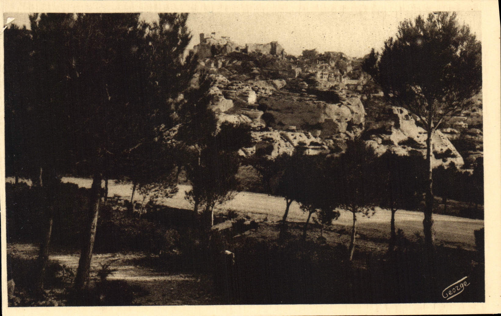 Les Baux - Vue sur l'ancienne cité — prise à travers les pins de la route de St-Remy — J. Georges, n°417