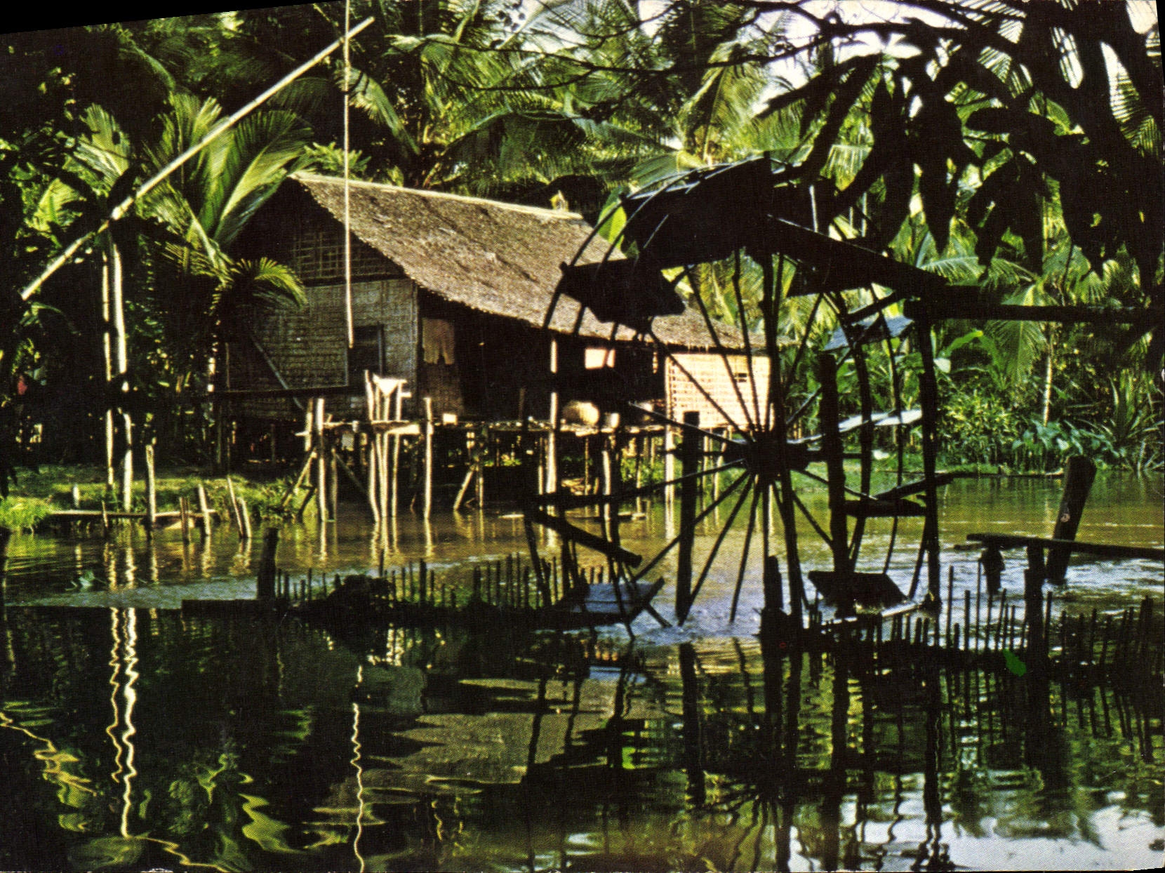 CPM Le Monde d'Angkor Habitation cambodgienne sur pilotis avec sa roue a aubes au bord de la riviere