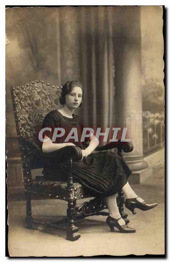 Jeune femme — en robe sombre et chaussures à talons — assise dans un fauteuil orné — studio photographique