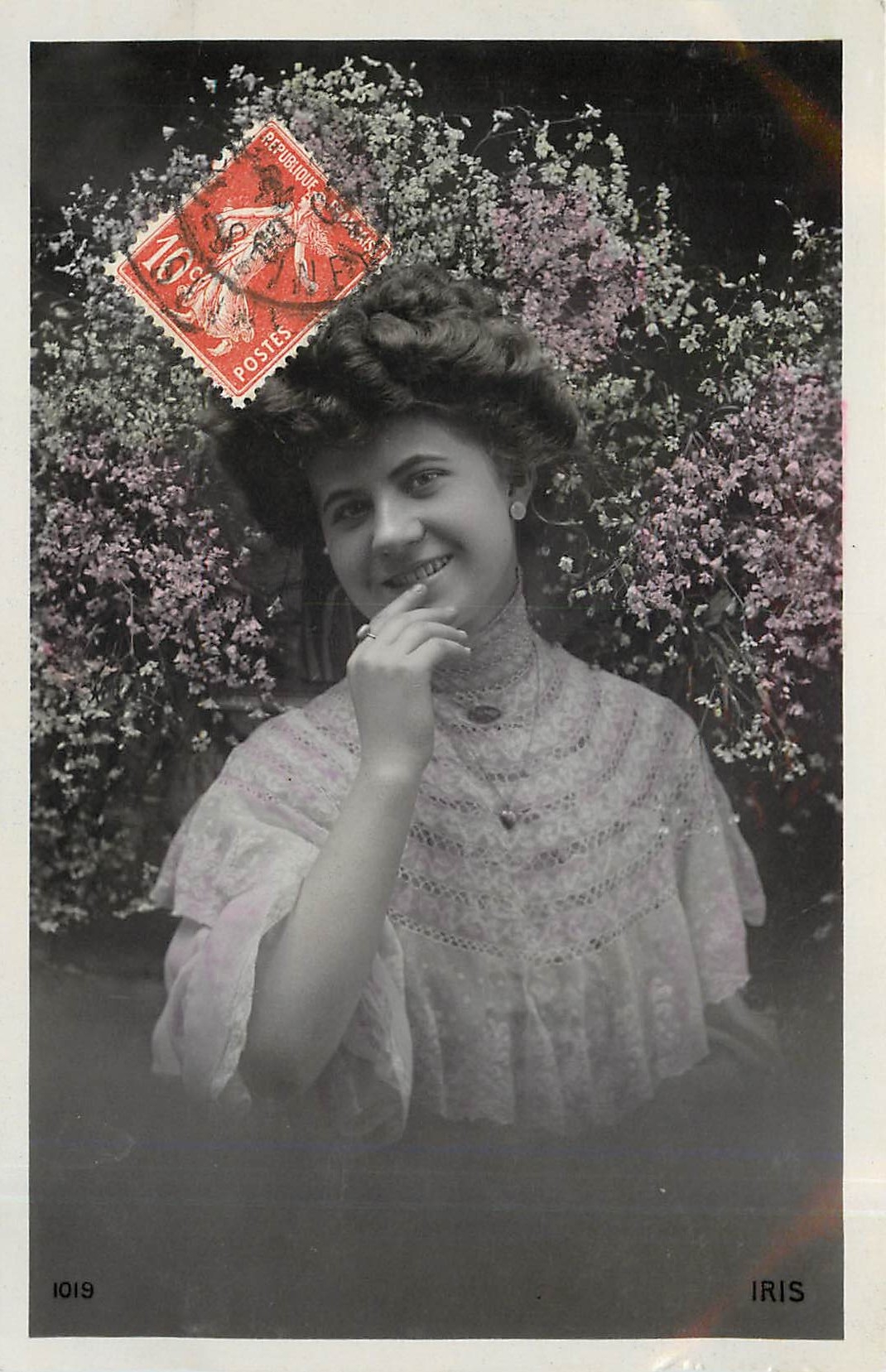 Jeune femme souriante — devant des fleurs — éditeur IRIS, n° 1019