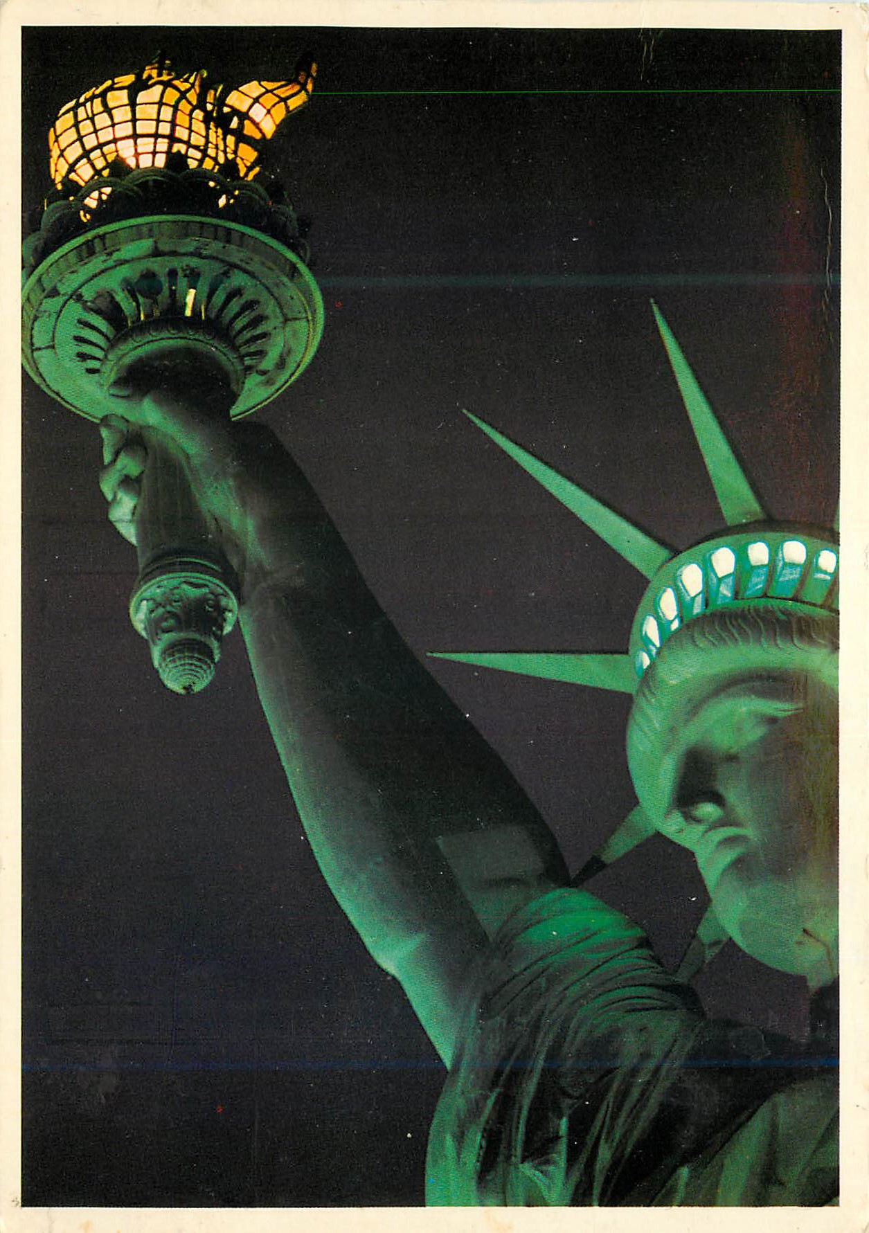 CPM a close up view of the head and torch of the statue of liberty brilliantly illuminated against a night sky in New yo