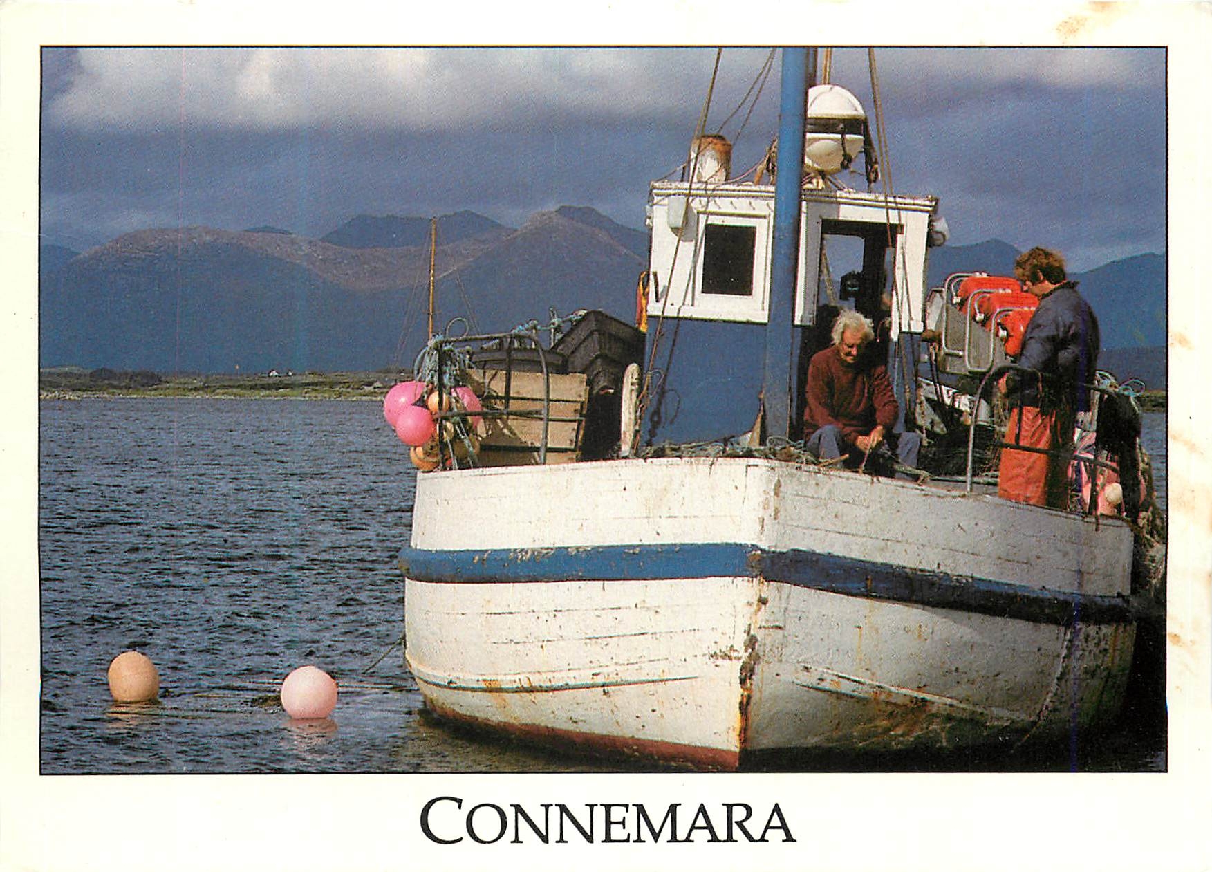 CPM Connemara Fishermen repairing their nets in Roundstone Harbour with the Twelve Pin Mountains of Connemara in the dis