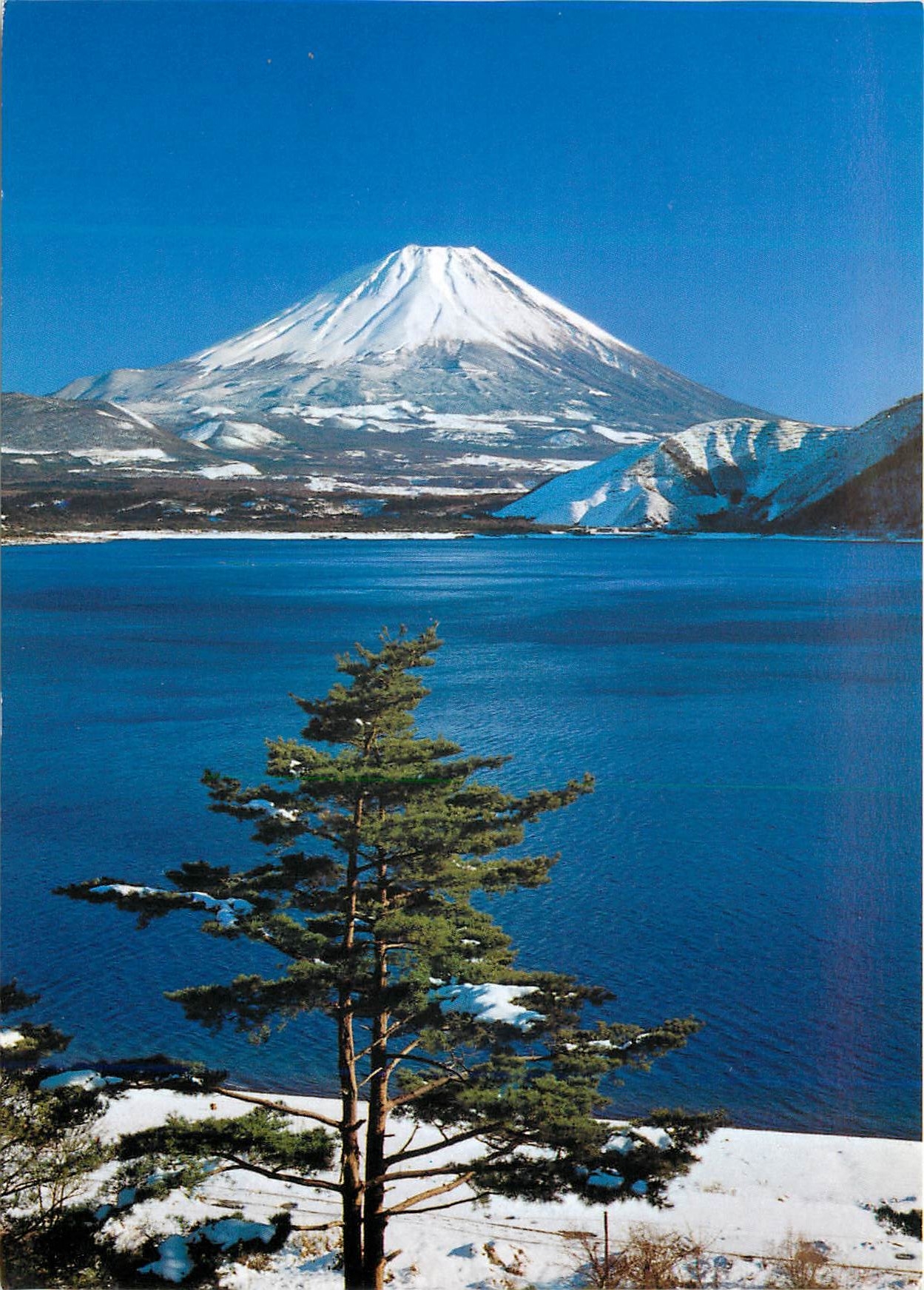 CPM Snow Covered Mt Fuji its Perfect Cone shape Against Blue Skies In the Foreground is Lake Motosu
