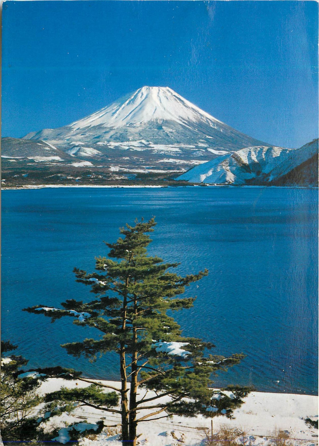 CPM Snow Covered Mt Fuji its Perfect Cone shape Against Blue Skies In the Foreground is Lake Motosu
