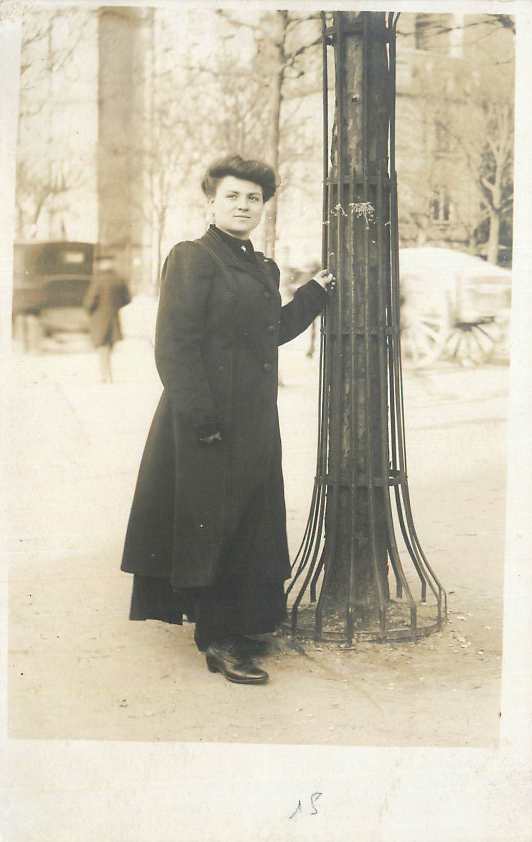 Femme en manteau noir — rue urbaine hivernale — numéro 18 visible en bas