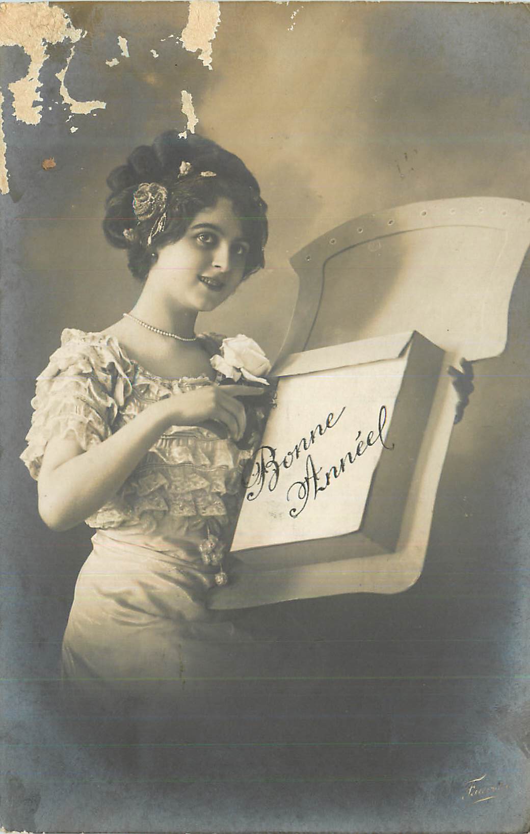 Jeune femme en robe à volants — tenant une boîte ouverte avec l'inscription 'Bonne Année' — éditeur F. Fournier