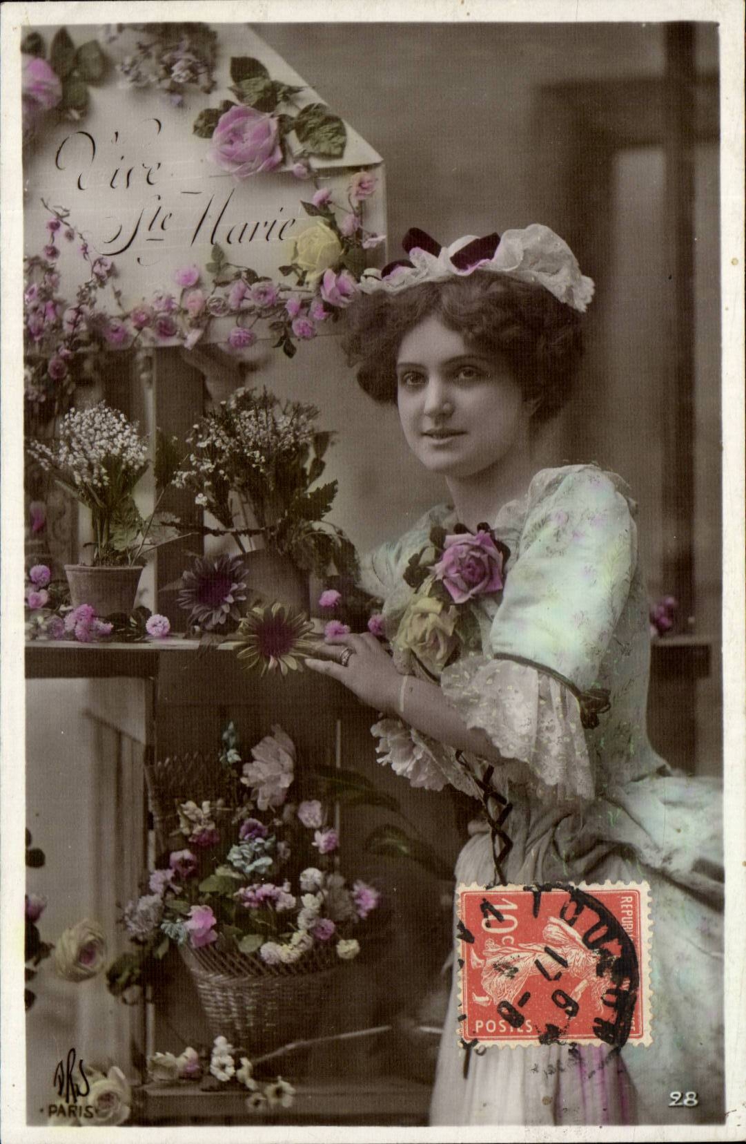 Femme en robe fleurie devant un étal de fleurs — 'Vie de Marie' — éditeur ARS, Paris, n°28