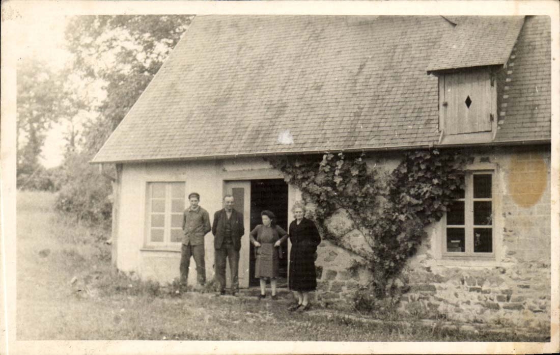 Quatre personnes devant une maison en pierre — éditeur CPAPHIL, n° de série non lisible