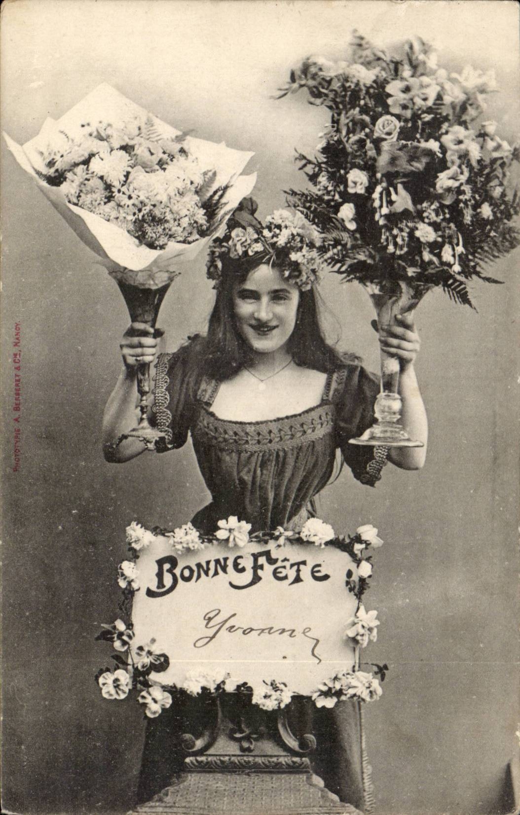 Femme en robe à col carré — tenant deux grands bouquets de fleurs — signée 'Bonne Fête Yvoanne' — Photographie A. Begenet & Cie, Nancy