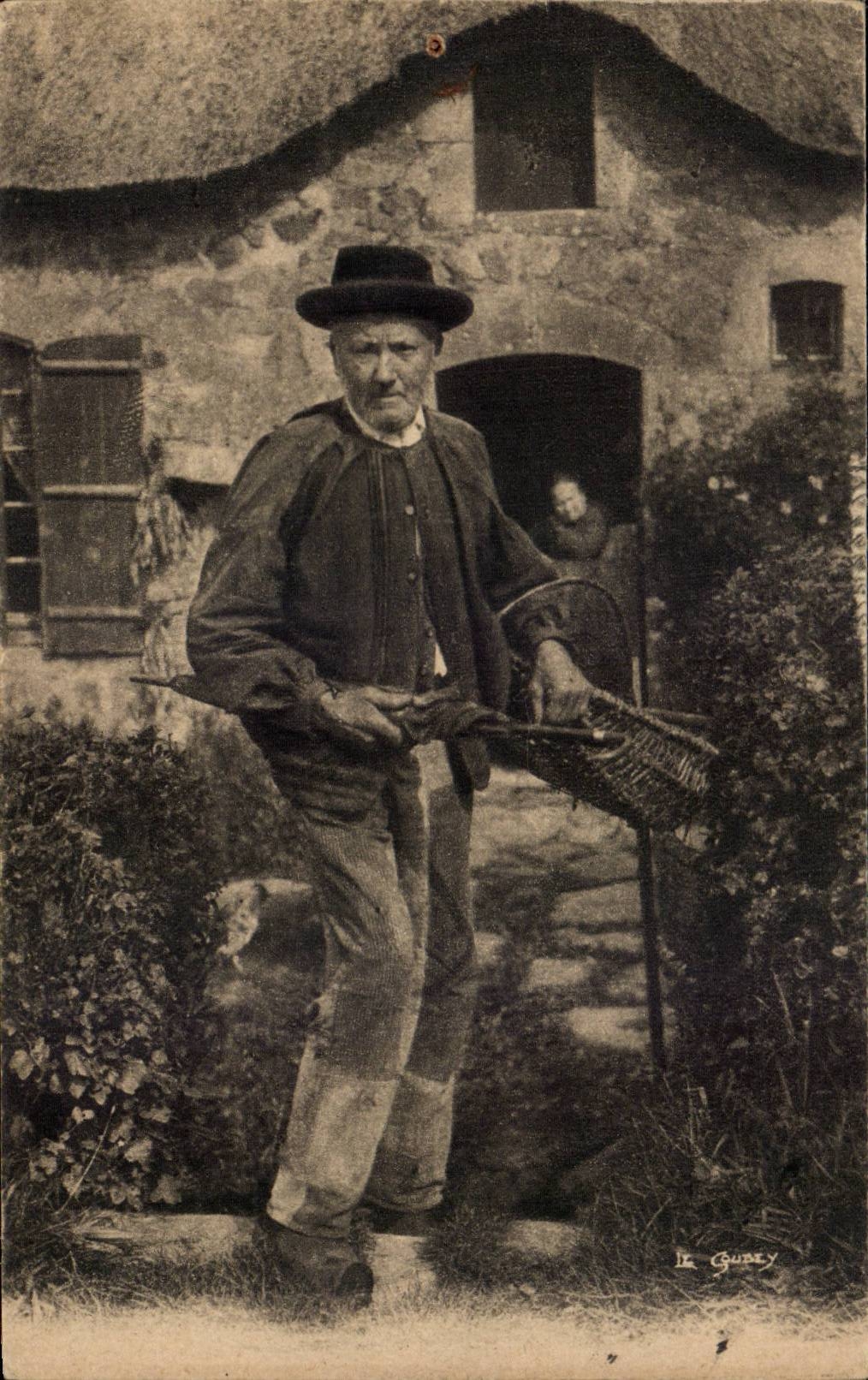Homme avec panier devant maison en pierre — Le Gubey — série 4585
