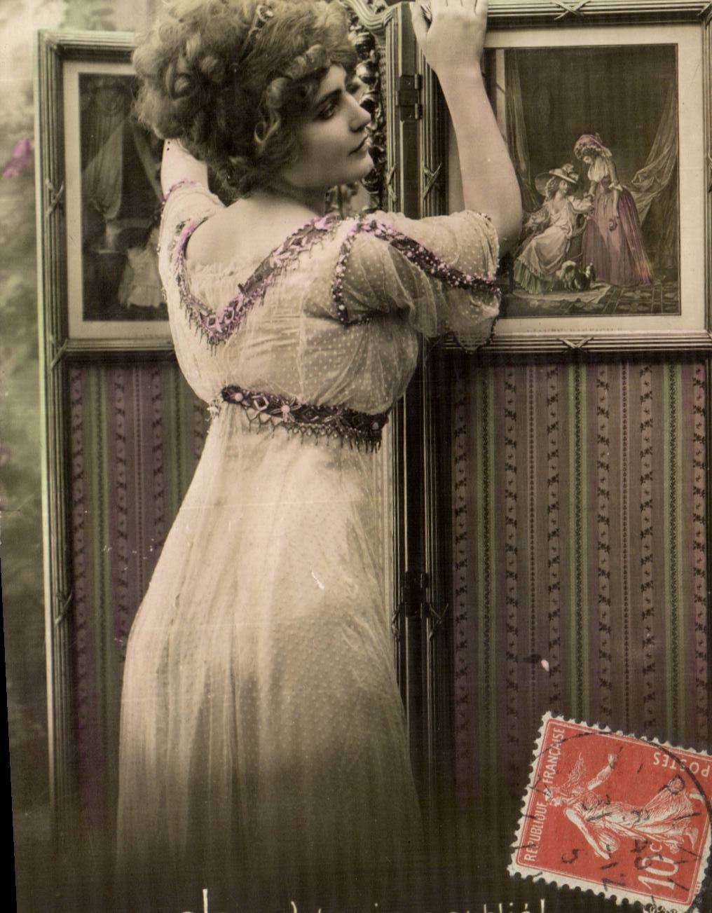 Femme en robe à broderies — intérieur décoré — éditeur inconnu, n° de série non visible