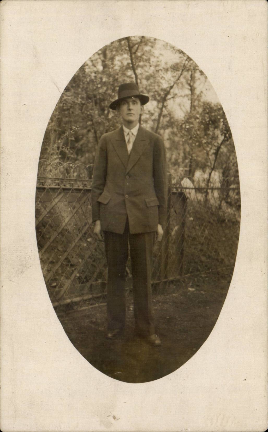 Homme en costume et chapeau — devant clôture métallique — carte postale Souvenir Douai