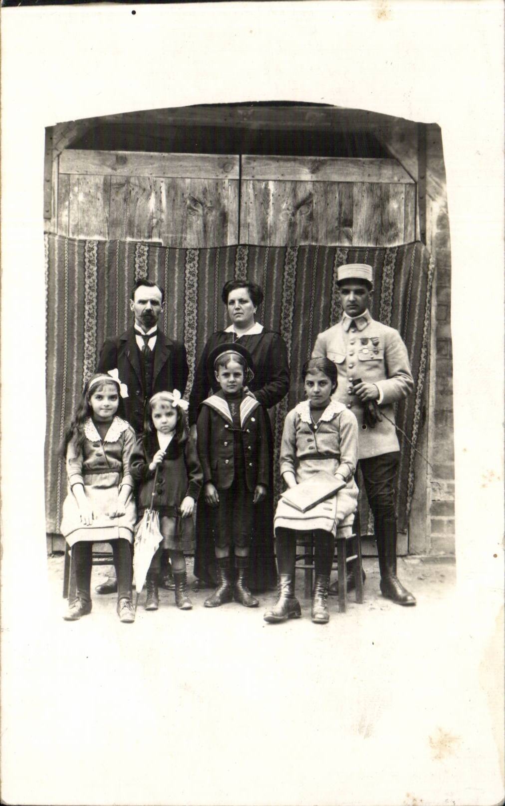 Famille avec soldat — devant une porte en bois — éditeur inconnu, n° de série non visible