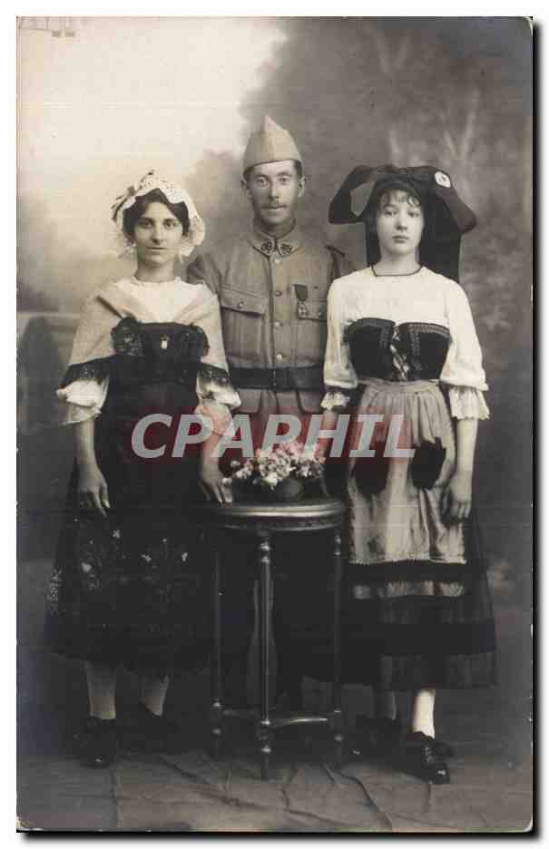 Portrait de trois personnes — homme en uniforme militaire entre deux jeunes femmes en tenues traditionnelles — éditeur non visible