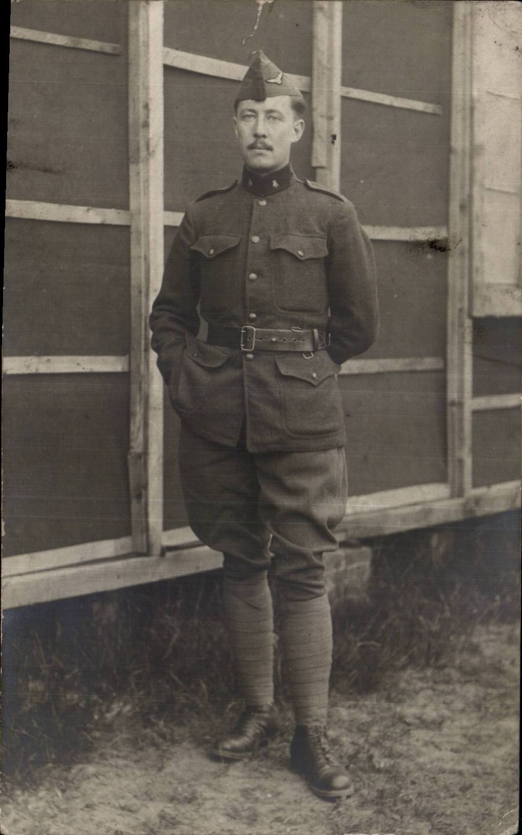 Soldat en uniforme — pose devant une structure en bois — carte postale