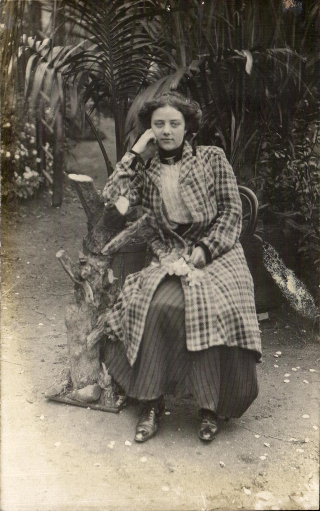 Jeune femme en manteau à carreaux — jardin tropical — Carte postale 'CARTE POSTALE' éditée par la Société des Cartes Postales