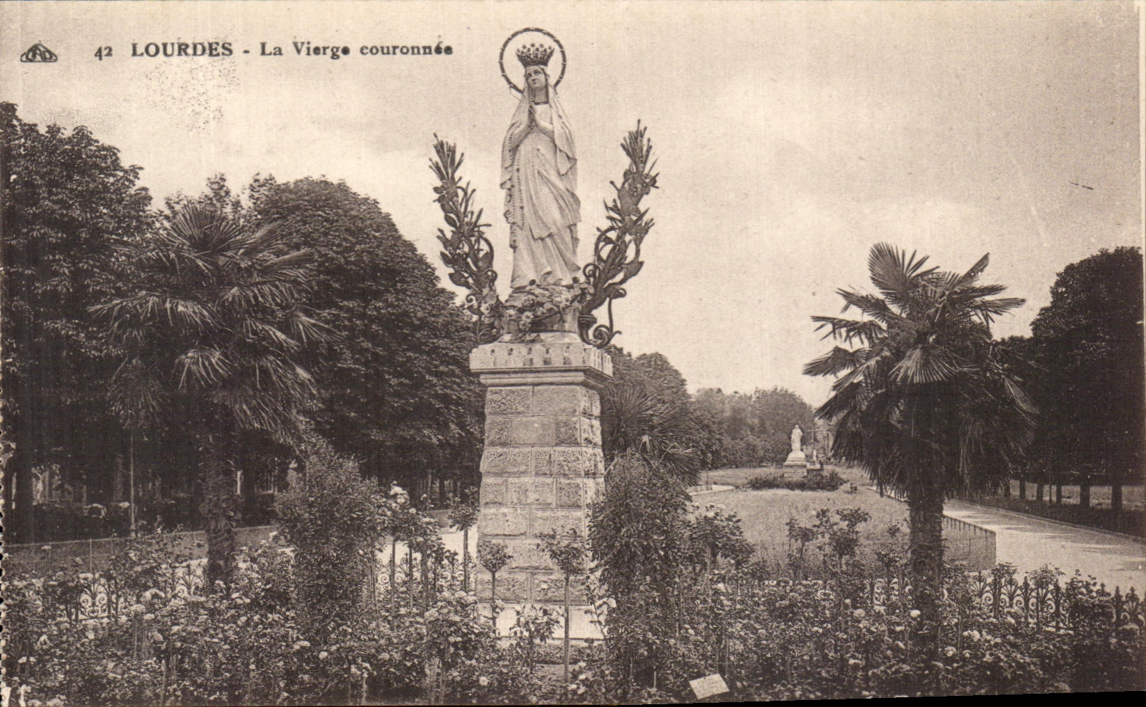 Lourdes - La Vierge couronnée — statue monumentale dans un parc avec palmiers