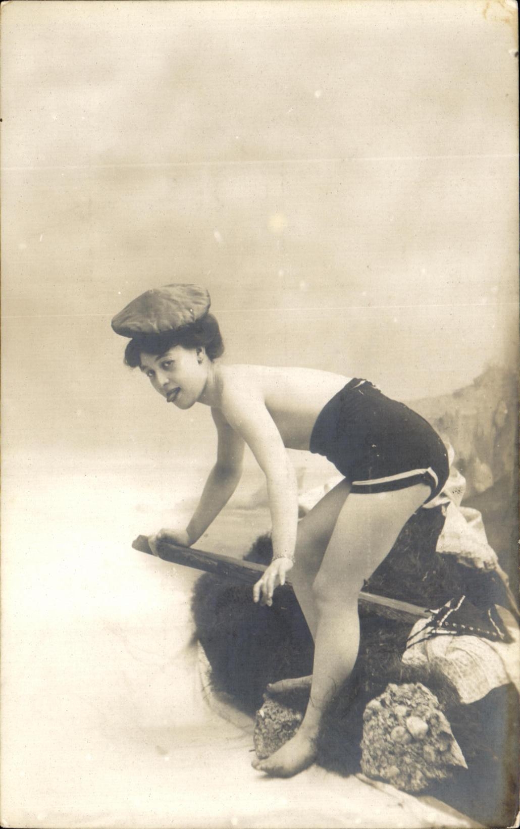 Jeune femme en maillot de bain et casquette — sur rochers — Carte postale CPAPHIL