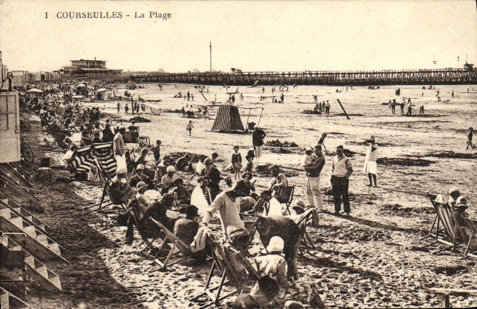 Courseulles - La Plage — vue de la plage animée avec un quai et un phare en arrière-plan