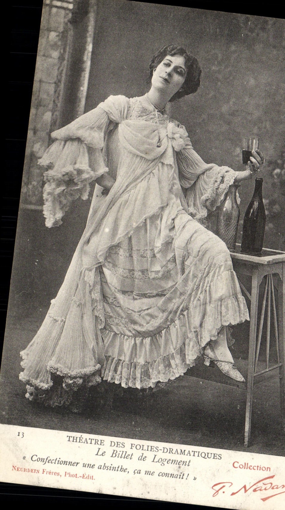 Sujet : Femme en robe de scène tenant une bouteille et un verre — Théâtre des Folies-Dramatiques — Collection Nadar, n°13 — Neurdein Frères, Phot.-Édit.