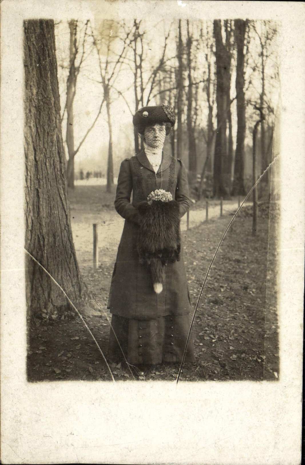 Femme en manteau et fourrure — parc boisé — sans éditeur ni numéro visible