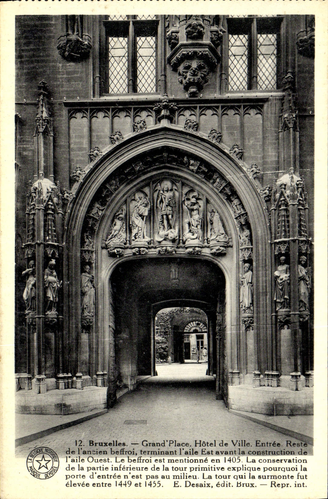 Bruxelles — Grand'Place. Hôtel de Ville. Entrée. Reste de l'ancien beffroi, terminant l'aile Ouest. Le beffroi est mentionné en 1405. La conservation de la partie inférieure de la tour primitive explique pourquoi la porte d'entrée n'est pas au milieu. La tour qui la surmonte fut élevée entre 1449 et 1455. — E. Desaix, édit. Brux. — Repr. int.