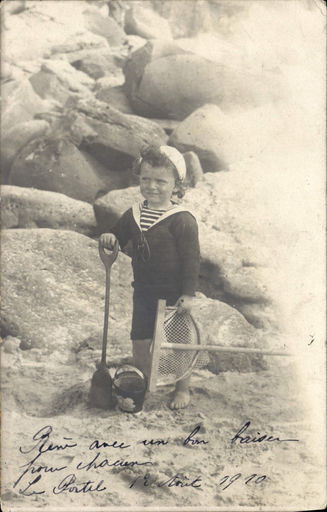 Niño en traje de marinero — playa rocosa — Le Patel, 1910