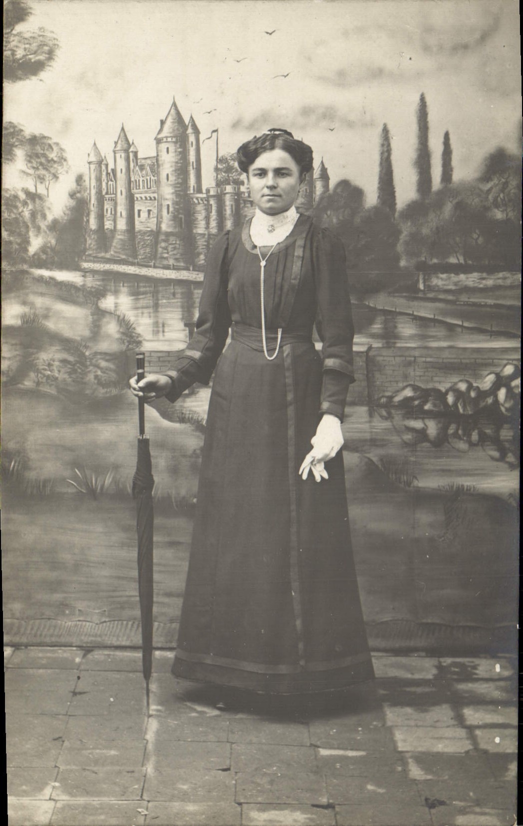 Femme en robe longue devant un décor de château — carte postale anonyme