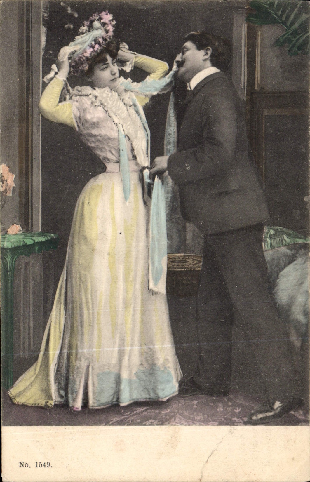Un homme ajuste un chapeau à une femme — scène intérieure — éditeur non identifié, n° 1549
