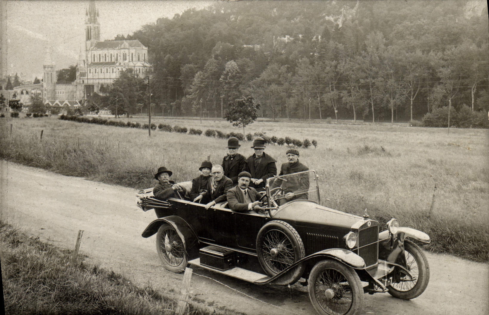 Groupe d'hommes dans une voiture ancienne — devant une église — éditeur inconnu, n° de série non visible