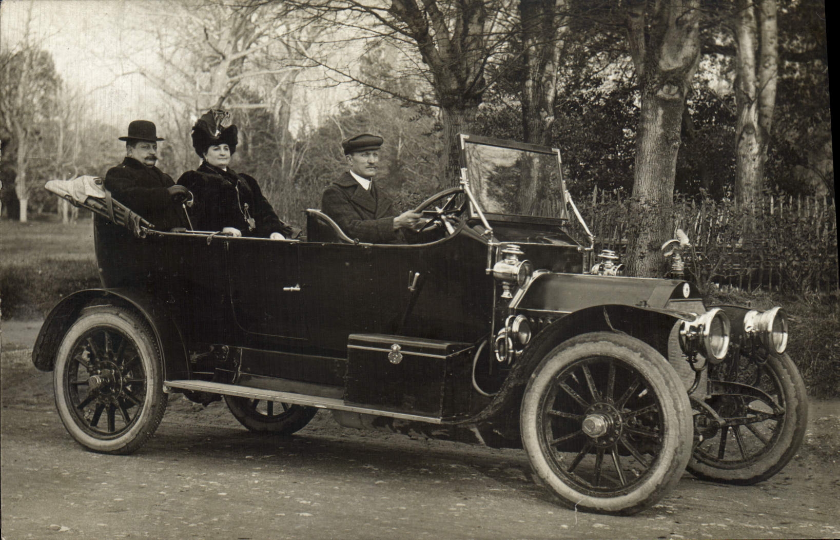 Trois personnes dans une voiture ancienne — éditeur et n° de série non lisibles