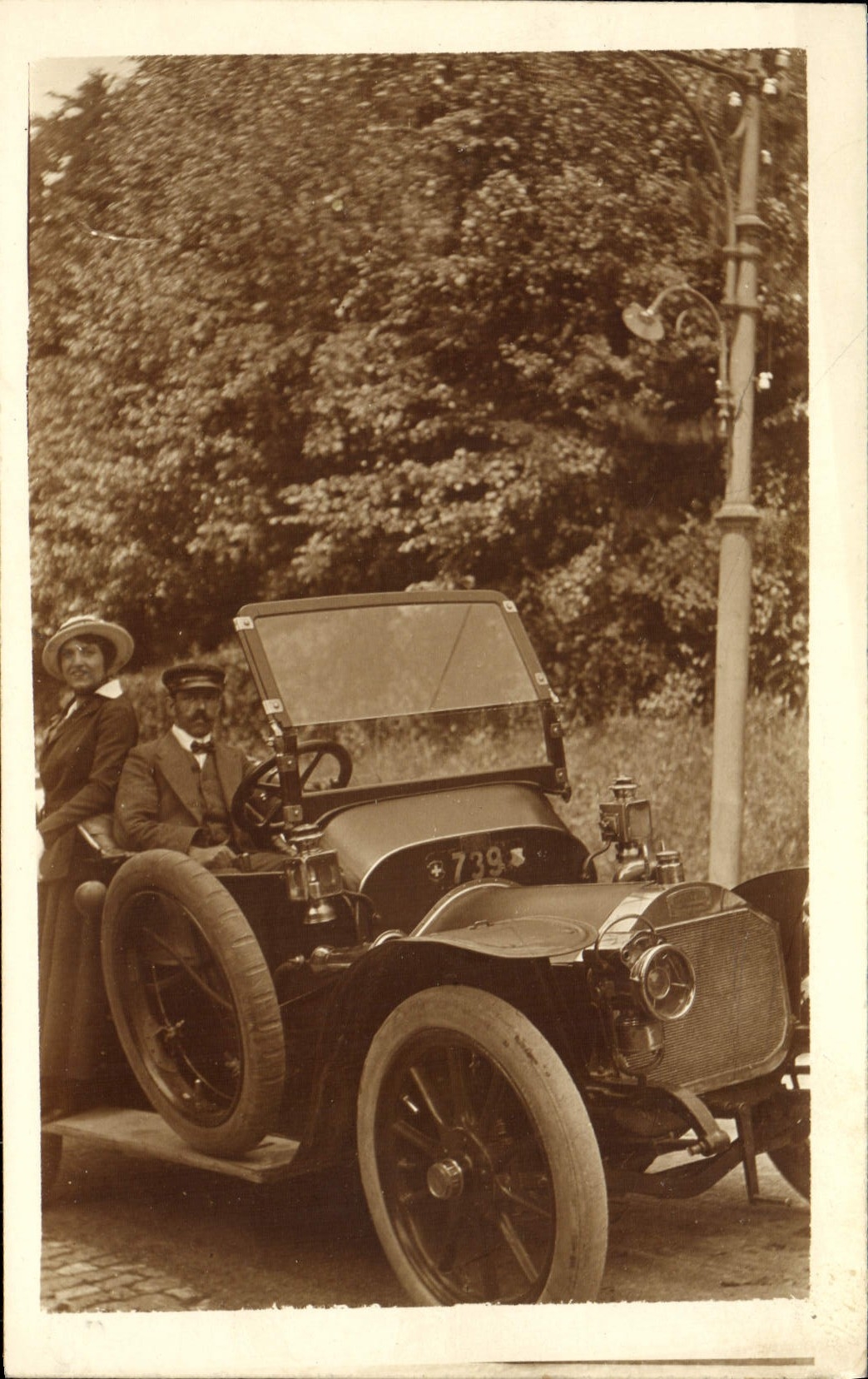 Automóvil antiguo — conductor y pasajera — editor desconocido, número de serie no visible