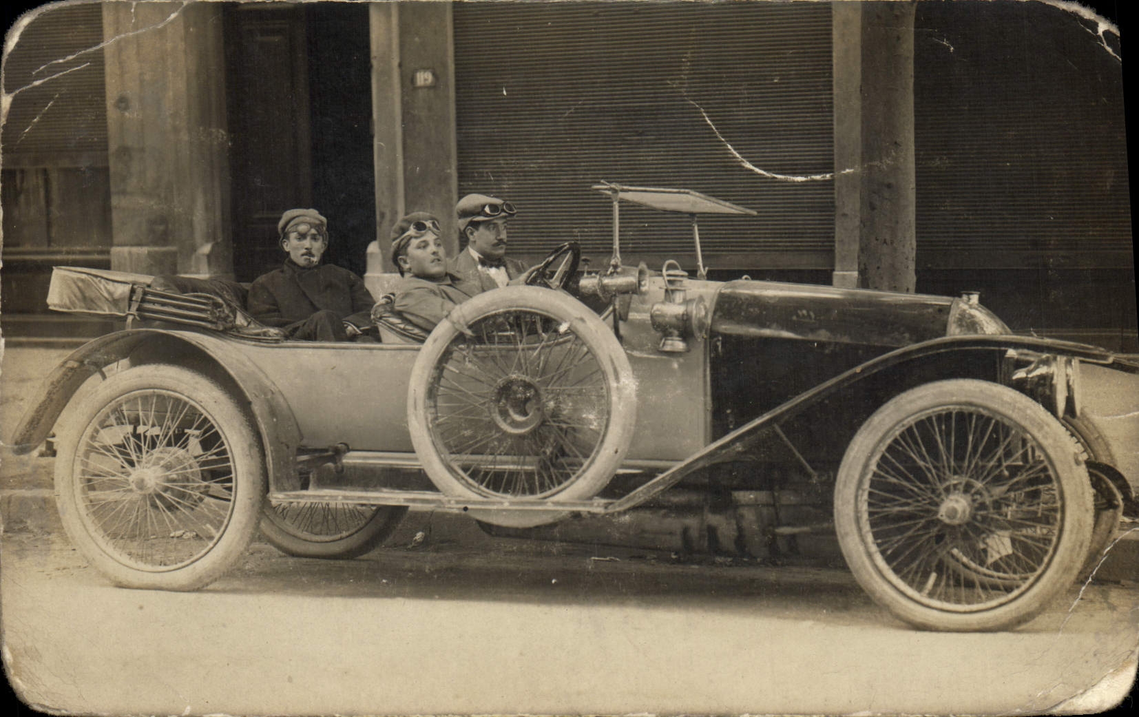 Trois hommes dans une voiture ancienne — éditeur inconnu, n° de série non visible