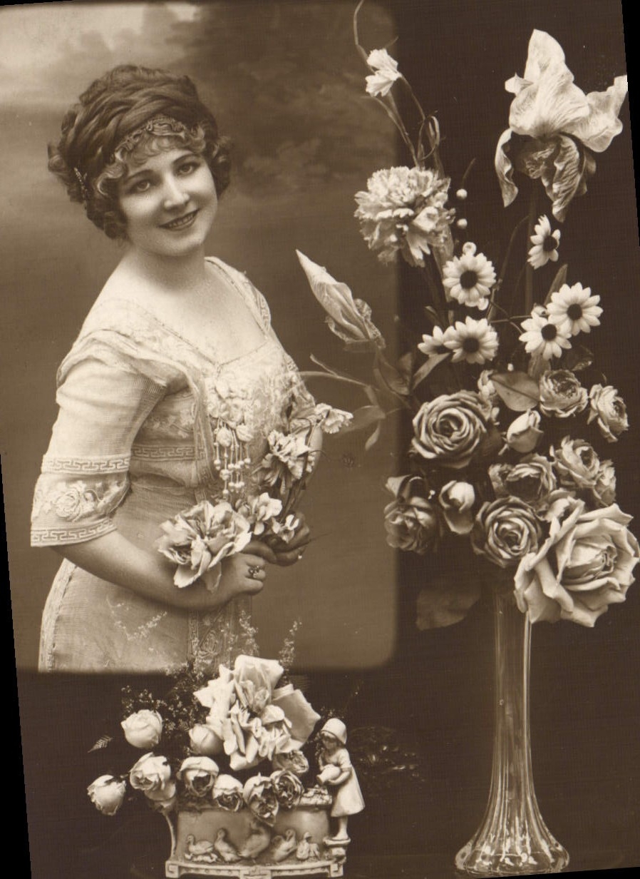 Woman in patterned dress — with bouquet and floral arrangement — postcard dated 24 June 1914