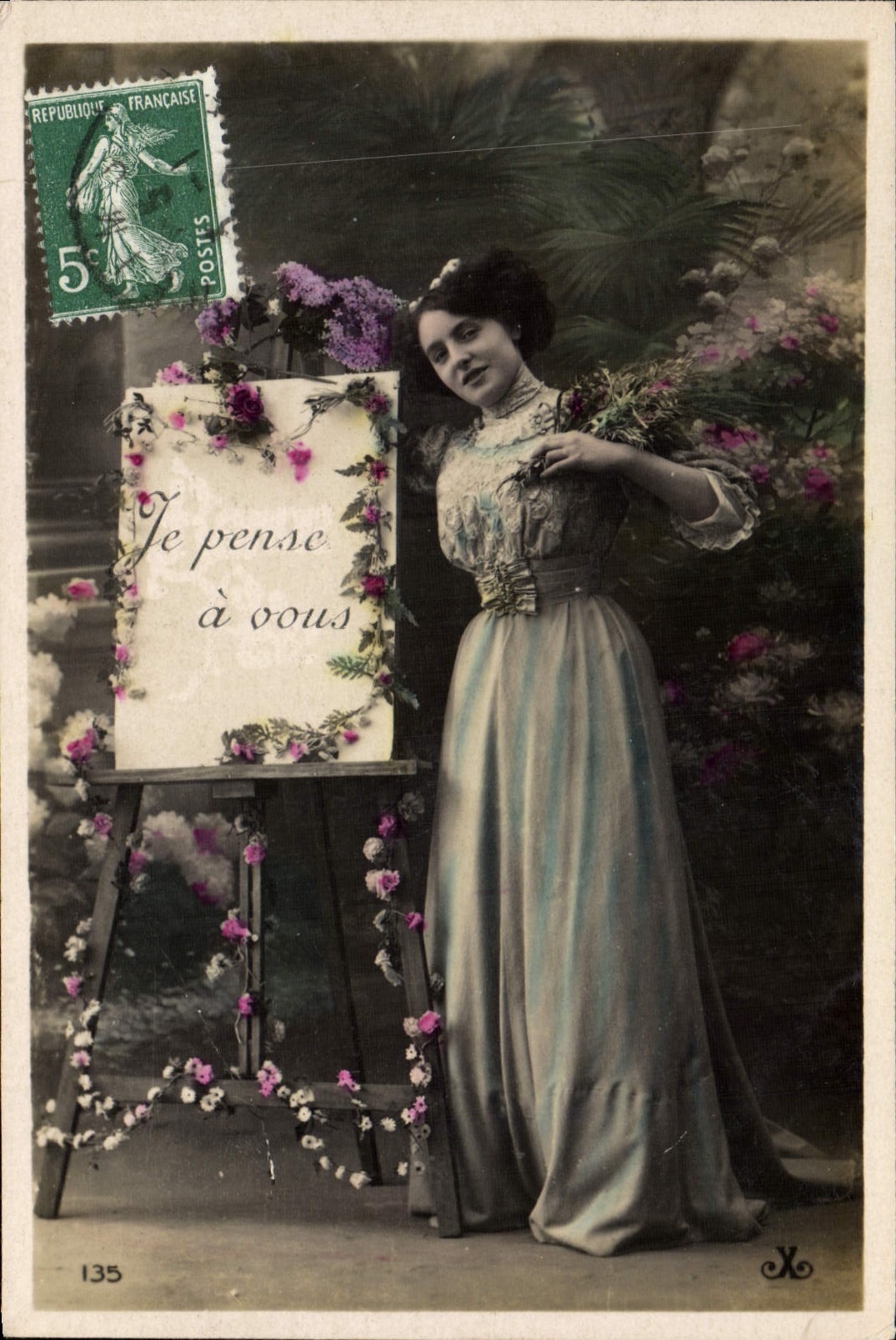 Mujer en vestido largo — frente a un cuadro decorado con flores — editor X, n° 135