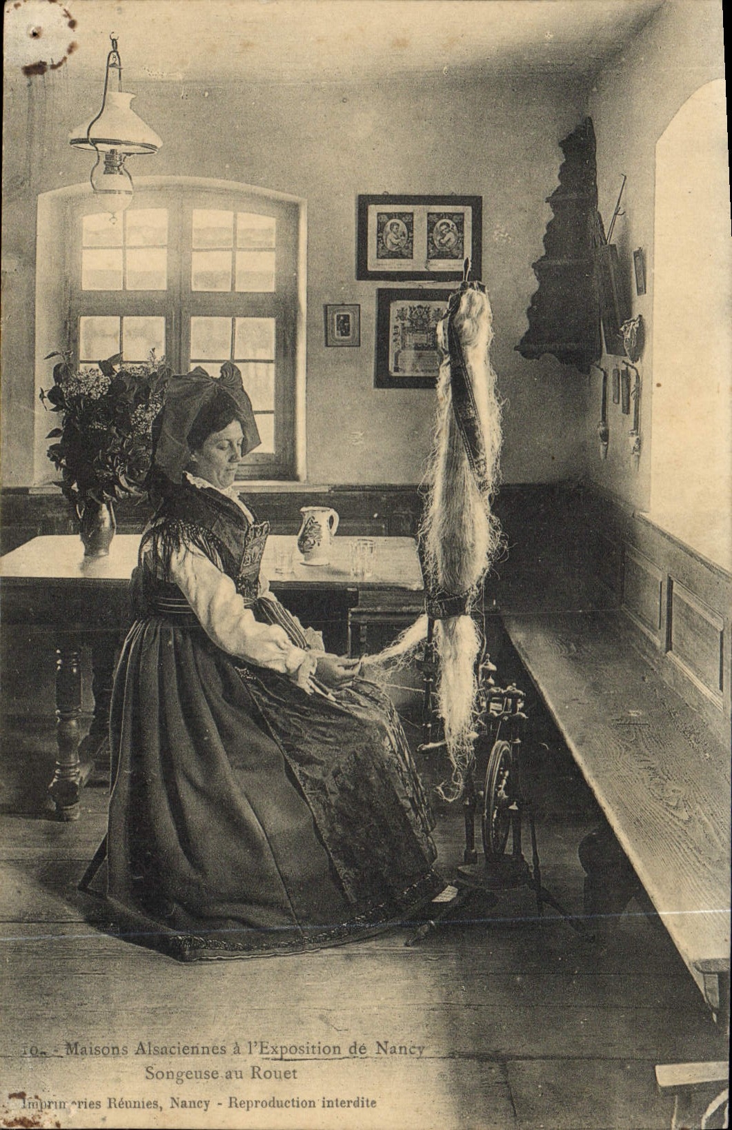 Femme alsacienne tissant à la roue — Exposition de Nancy — Imprimeries Réunies, Nancy