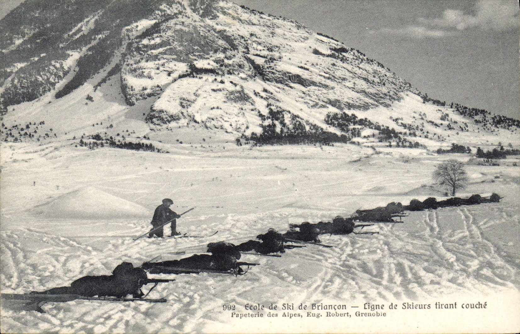 Escuela de Esquí de Briançon — Línea de Esquiadores tumbados disparando — Papeterie des Alpes, Eug. Robert, Grenoble