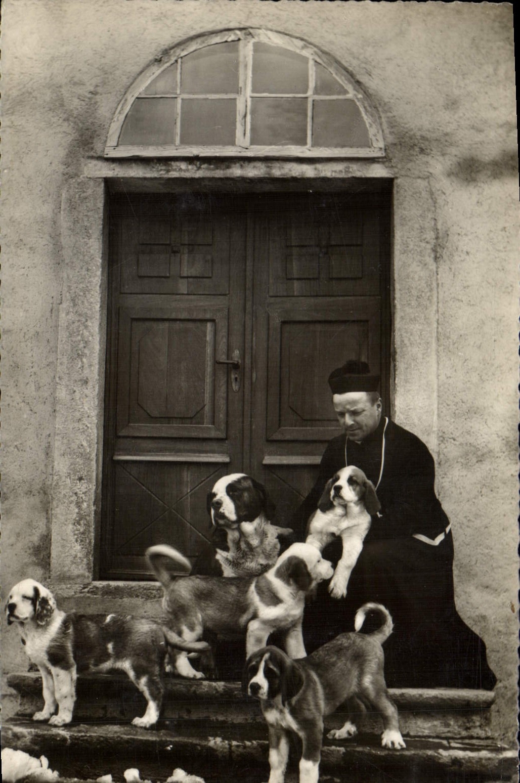 Père religieux avec chiots — devant une porte — Édition Jaeger Genève