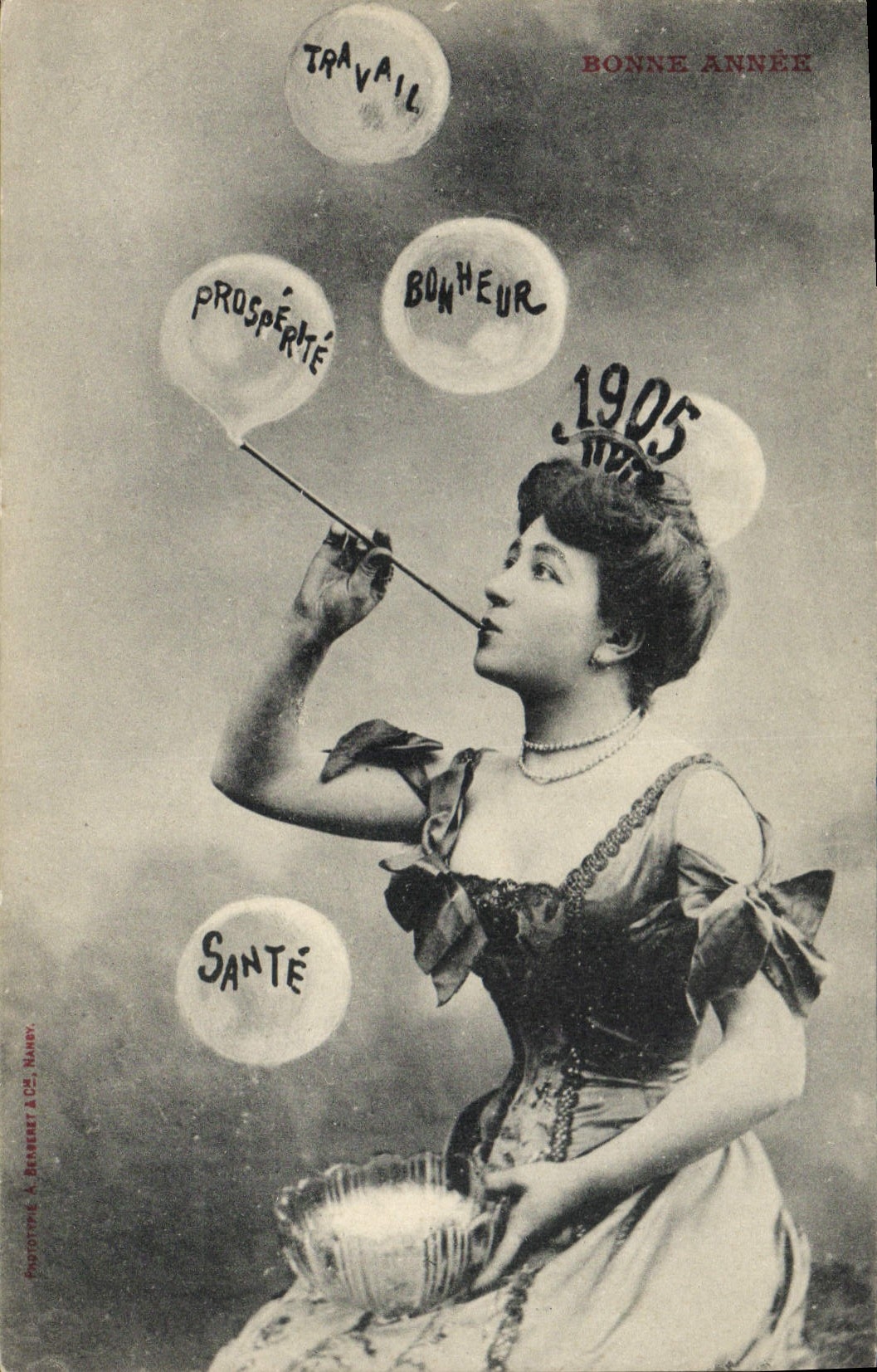 Femme soufflant des bulles avec les mots Travail, Bonheur, Prospérité, Santé — Bonne Année 1905 — Phototypie A. Bernelet & Cie, Nancy