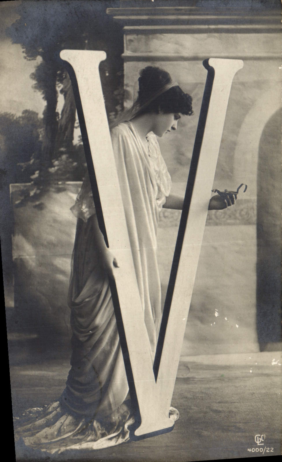 Femme en robe antique près d'une grande lettre V — GC 4000/22