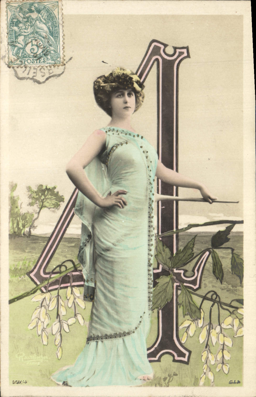 Femme en robe bleue — devant une grande lettre 'A' — éditée par S.L.A.