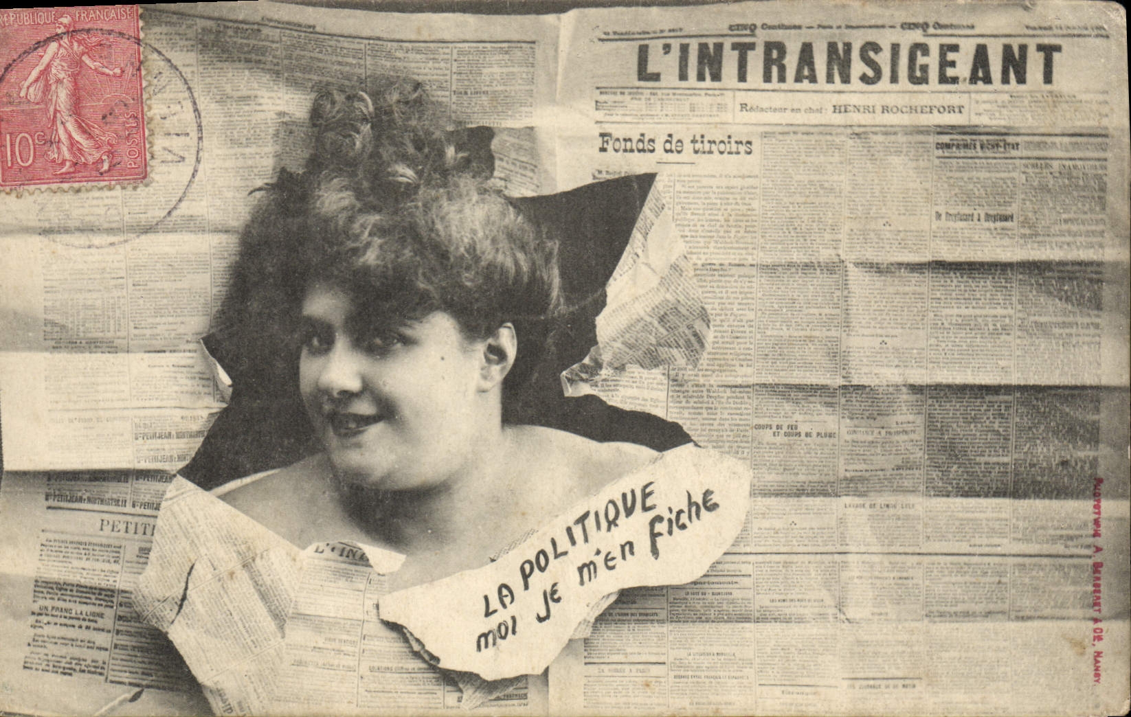 Femme souriante — avec texte « LA POLITIQUE MOI JE m'en fiche » — sur fond de journal L'INTRANSIGEANT — éditeur A. BARRETT & Cie, Nancy