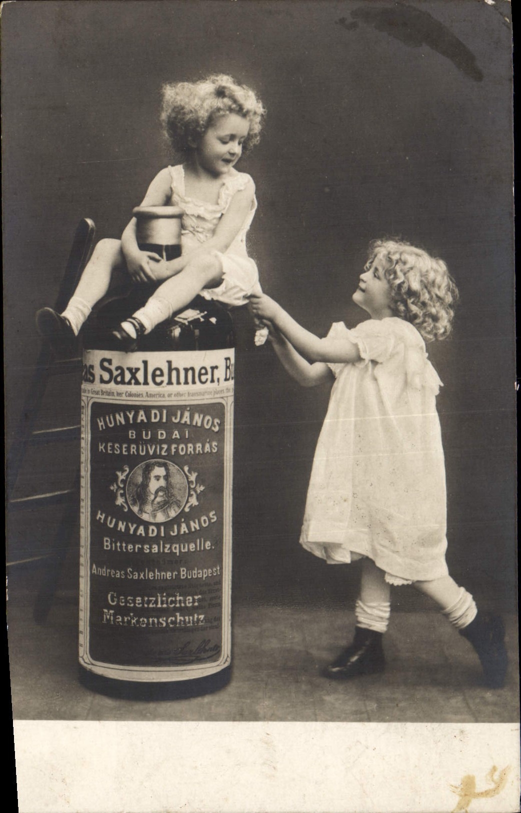 Deux enfants jouant avec une bouteille géante de Hunyadi János — publicité pour le bittersalzquellen de Budapest — éditeur inconnu