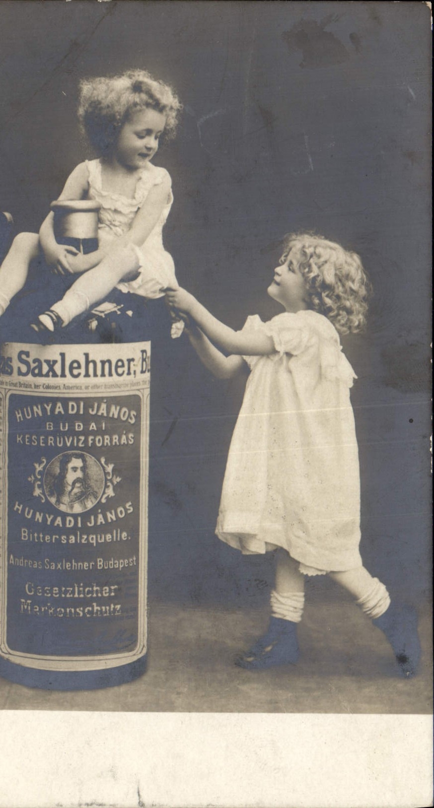 Deux enfants jouant avec une bouteille publicitaire — Hunyadi János Budaï Késerűvíz Forrás — éditeur inconnu